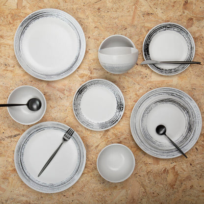 Set of ceramic plates and bowls with black rim designs on a wooden surface