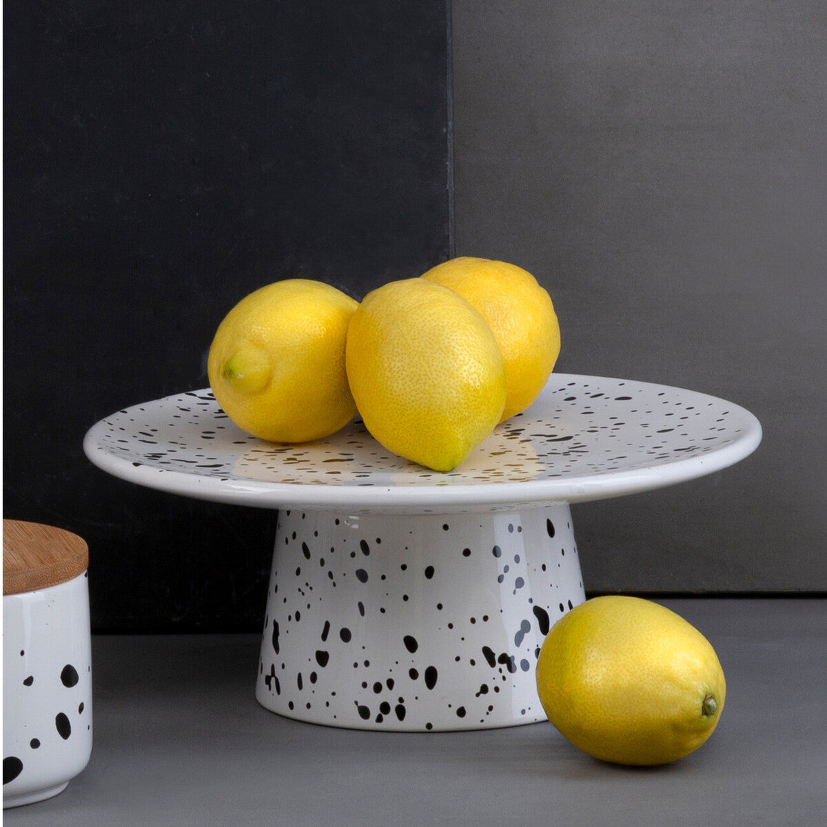 Speckled ceramic cake stand with lemons on a dark background