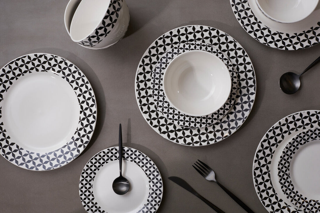Black and white patterned ceramic plates on a gray surface with cutlery.