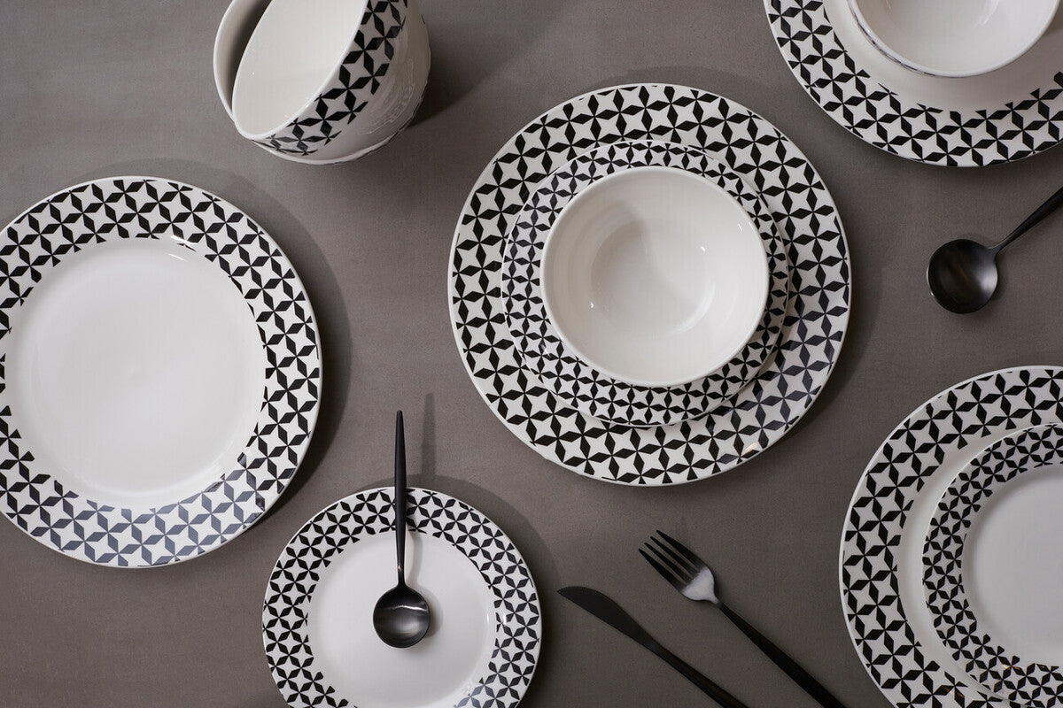 Black and white patterned ceramic plates on a gray surface with cutlery.