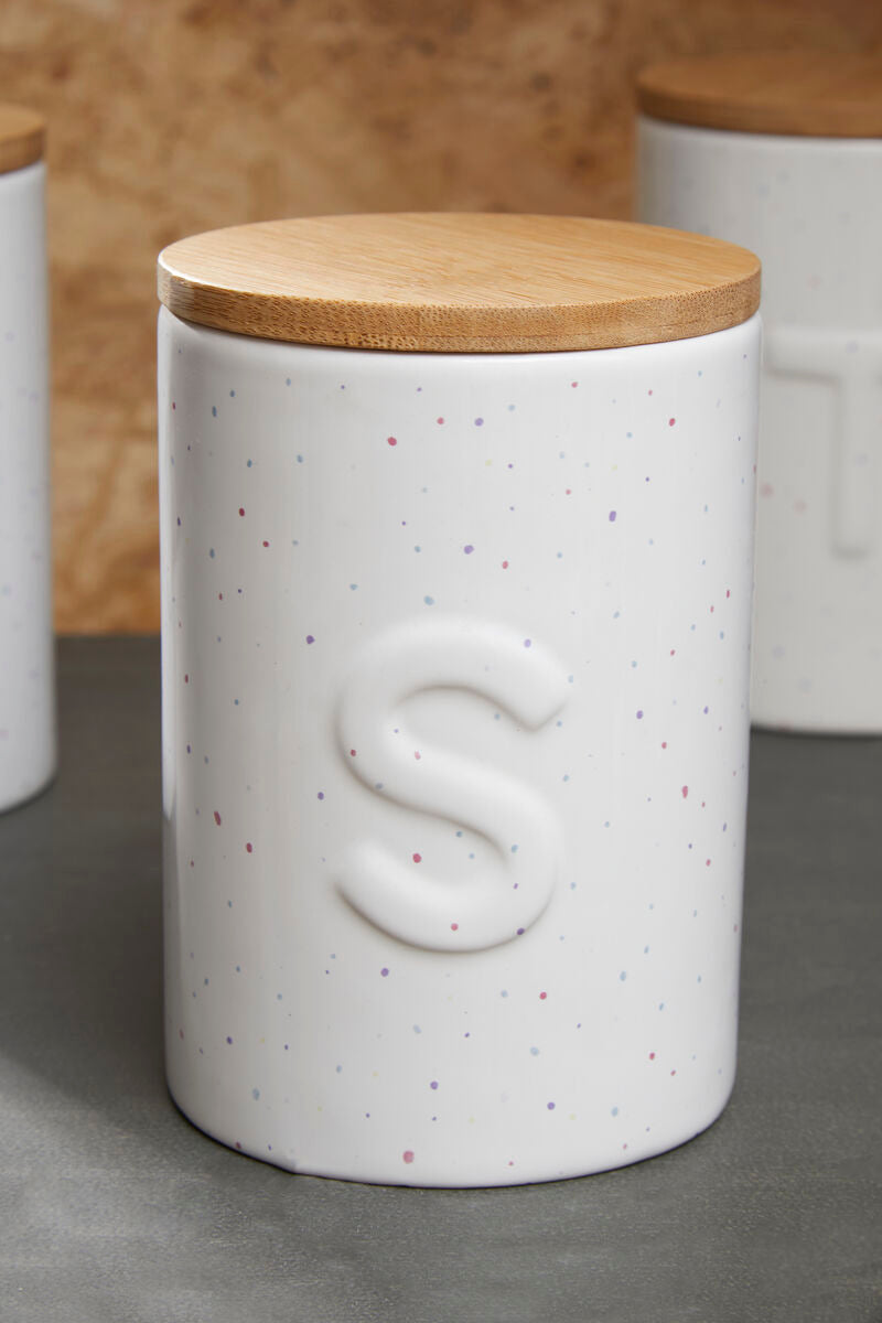 White speckled ceramic jar with a wooden lid on a gray surface.