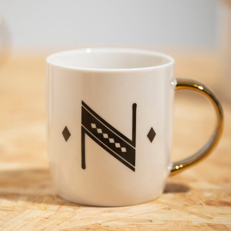 White mug with black geometric design on a wooden surface
