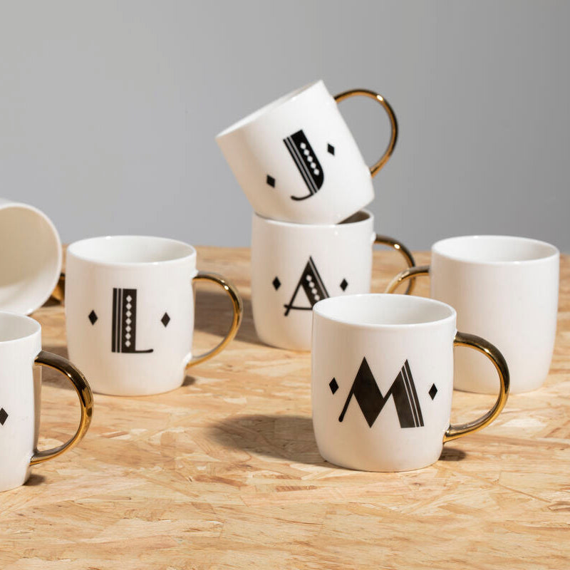 Set of white mugs with black letter designs on a wooden surface