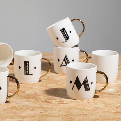 Set of white mugs with black letter designs on a wooden surface