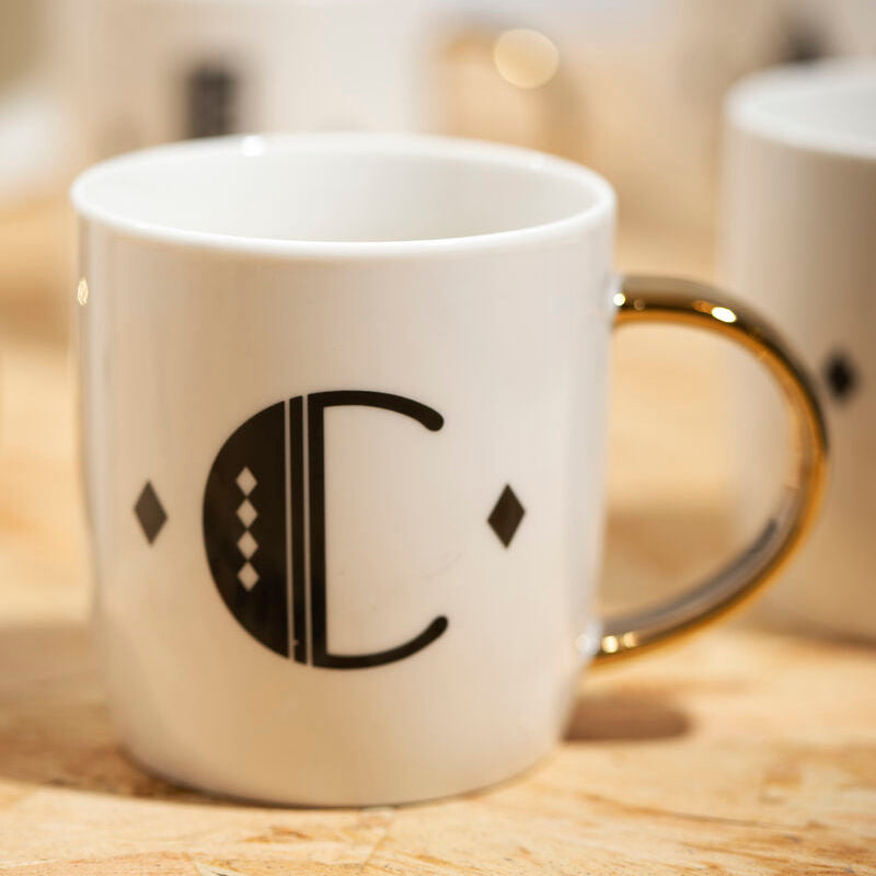 White mug with a black logo on a wooden surface