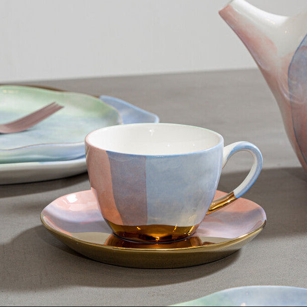 Ceramic teapot and cup set with a gradient design on a gray surface.