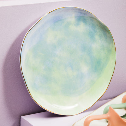 Round ceramic plate with a pastel gradient design on a white surface.