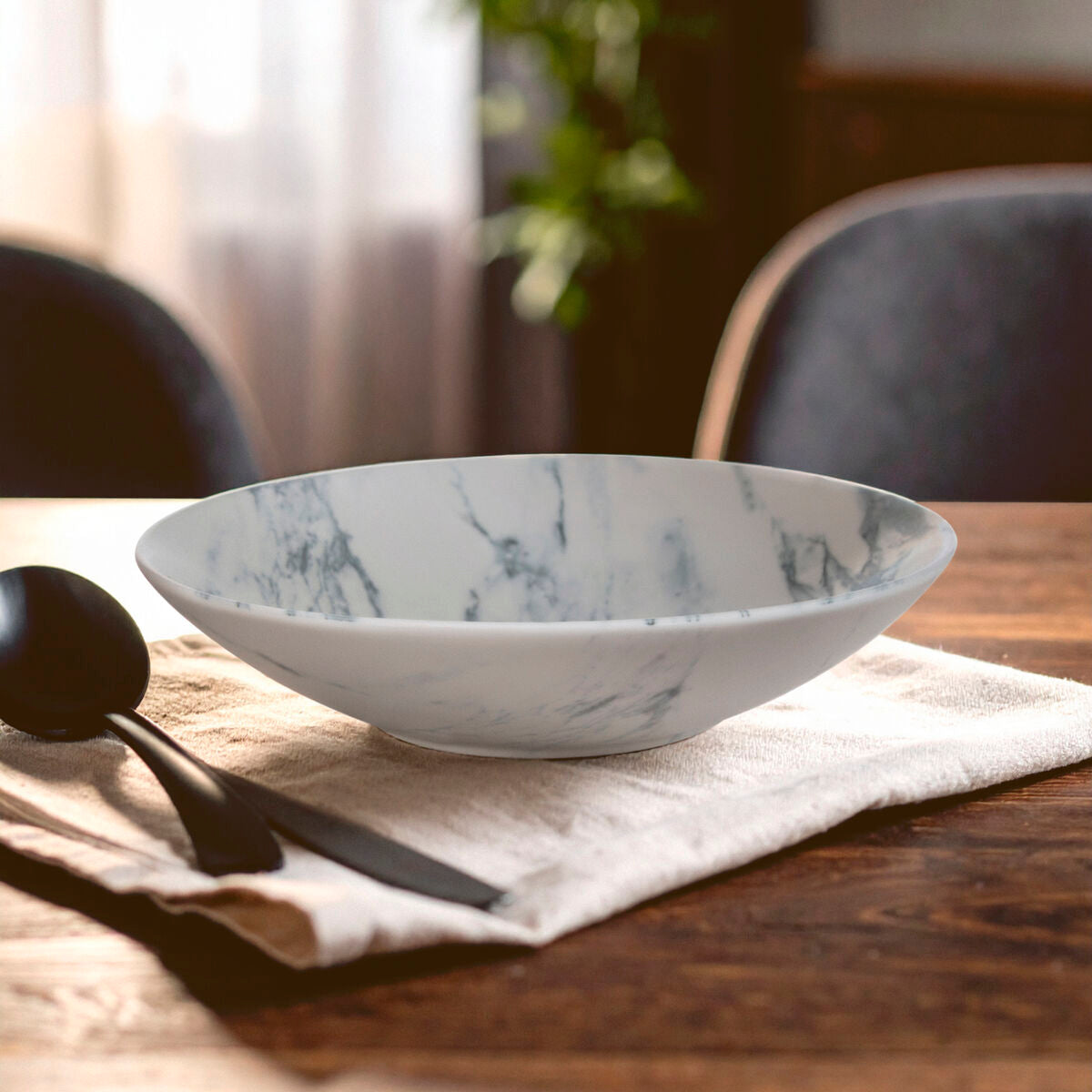 Marble-patterned ceramic bowl on a wooden table with a cloth and spoon