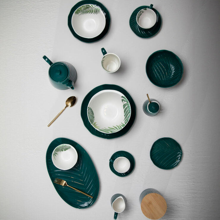 Collection of green ceramic dishes and tableware on a gray background