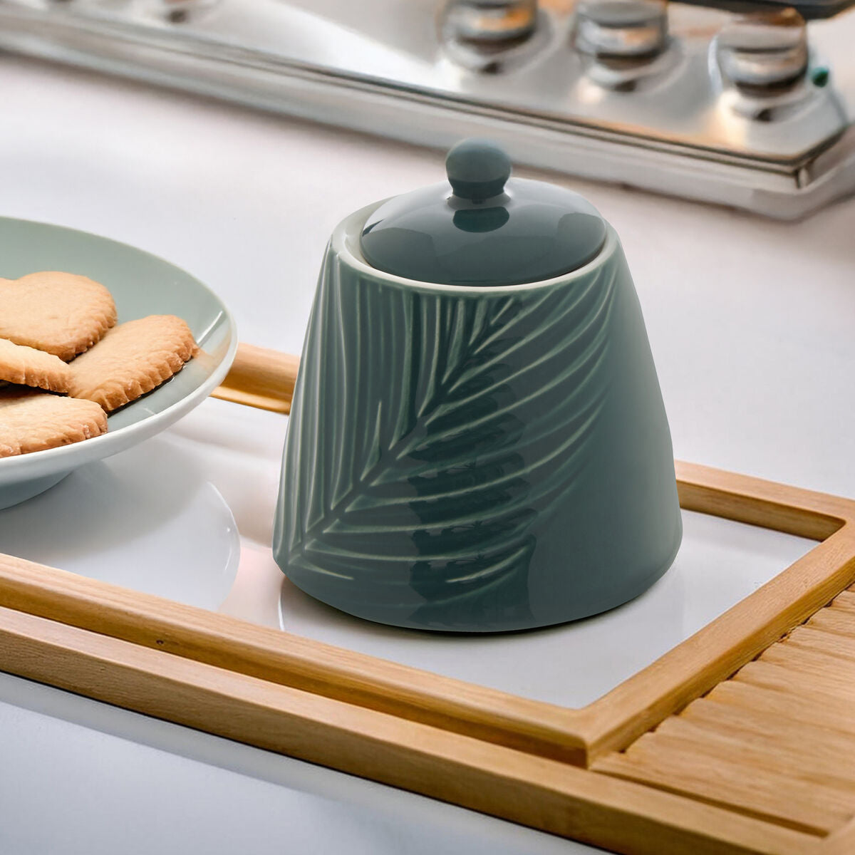 Green ceramic container with leaf patterns on a kitchen counter