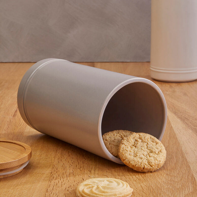 Gray cylindrical cookie jar with cookies on a wooden surface
