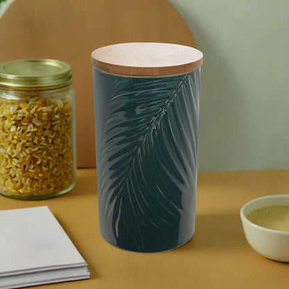 Ceramic container with leaf design on a table with a jar and bowl in the background