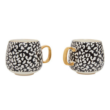 Two ceramic mugs with black and white pattern and gold handles on a white background