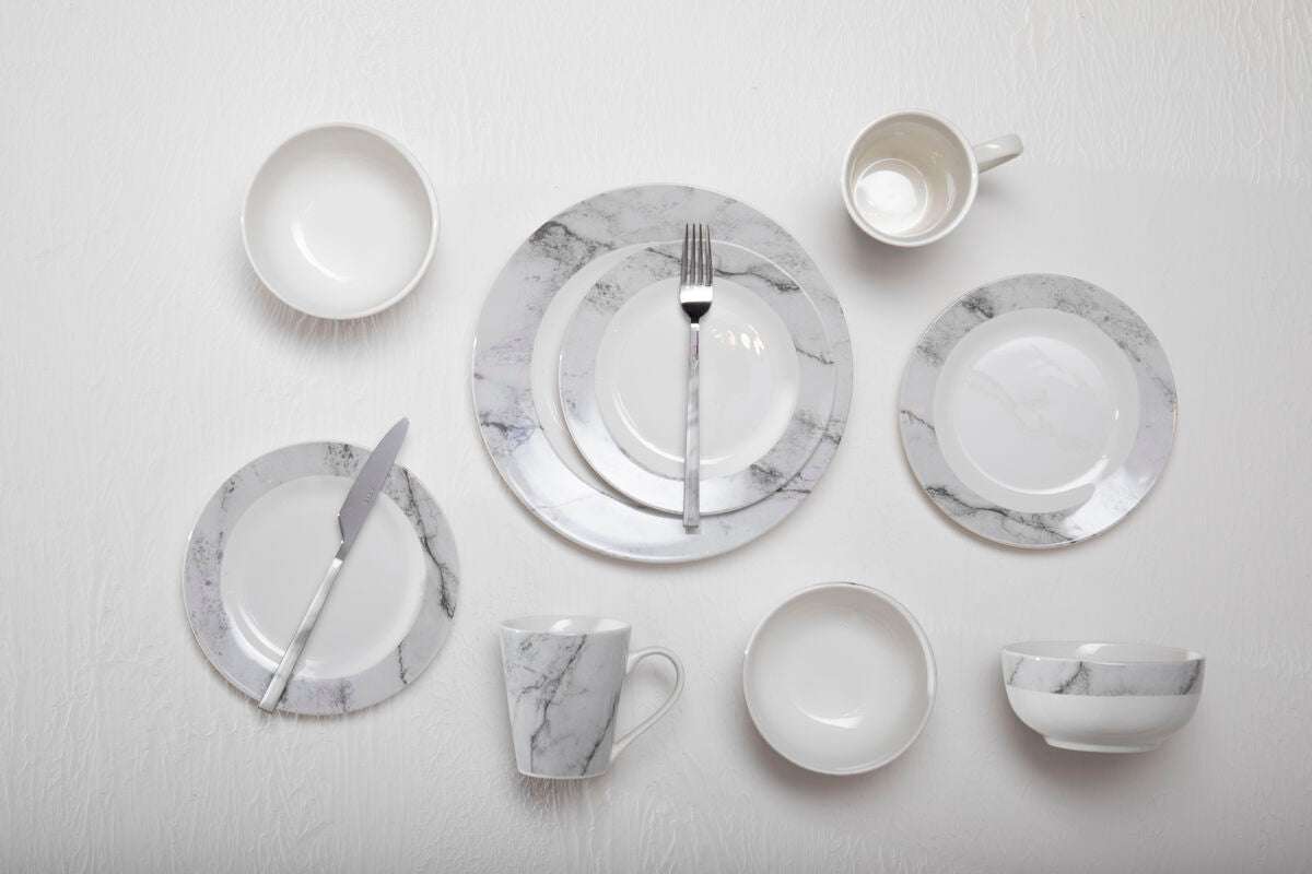 Set of marble-patterned ceramic dinnerware on a light gray background