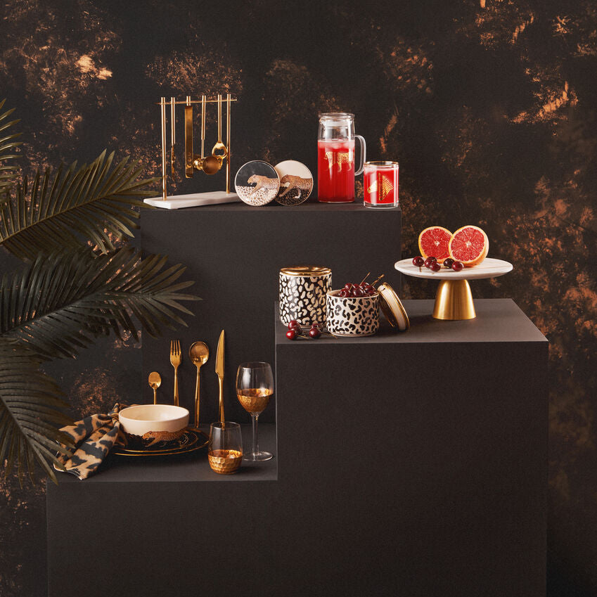Decorative table setting with candles, fruit, and gold accents against a dark background