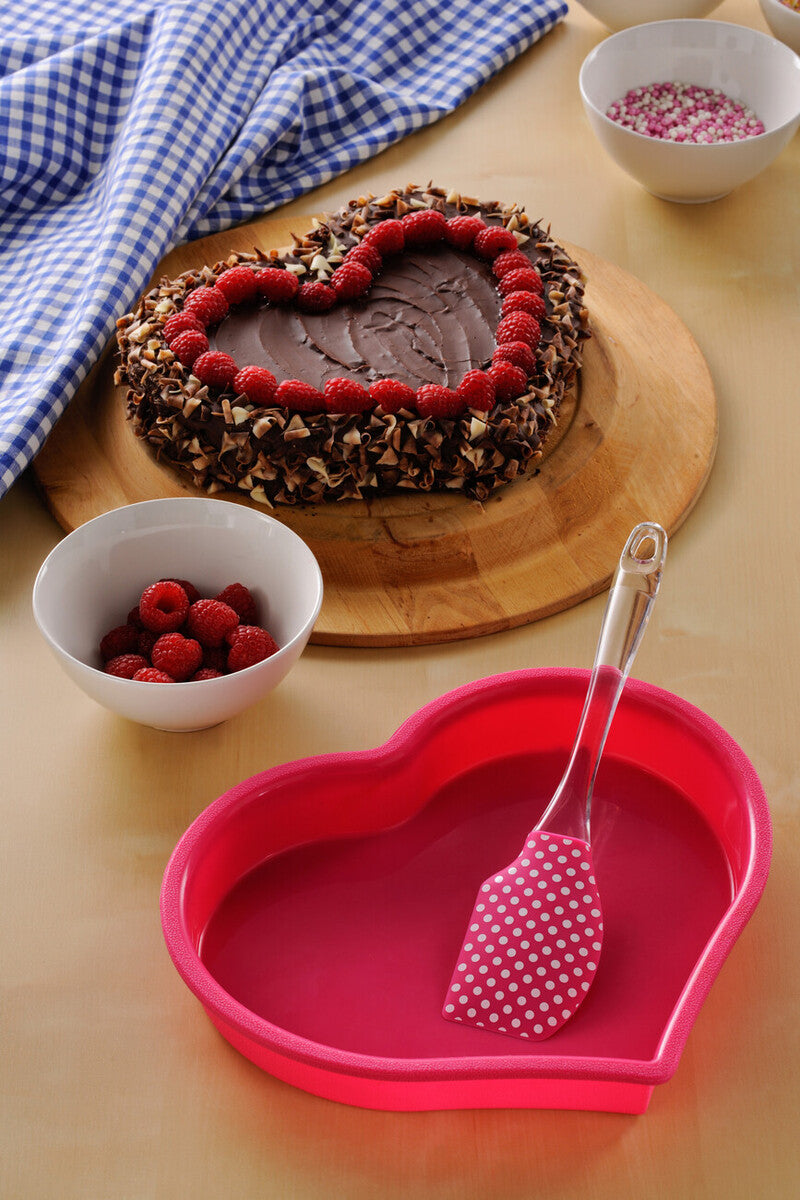 Heart-shaped chocolate cake with raspberries on a wooden board, surrounded by bowls of raspberries and a pink heart-shaped dish with a spoon.