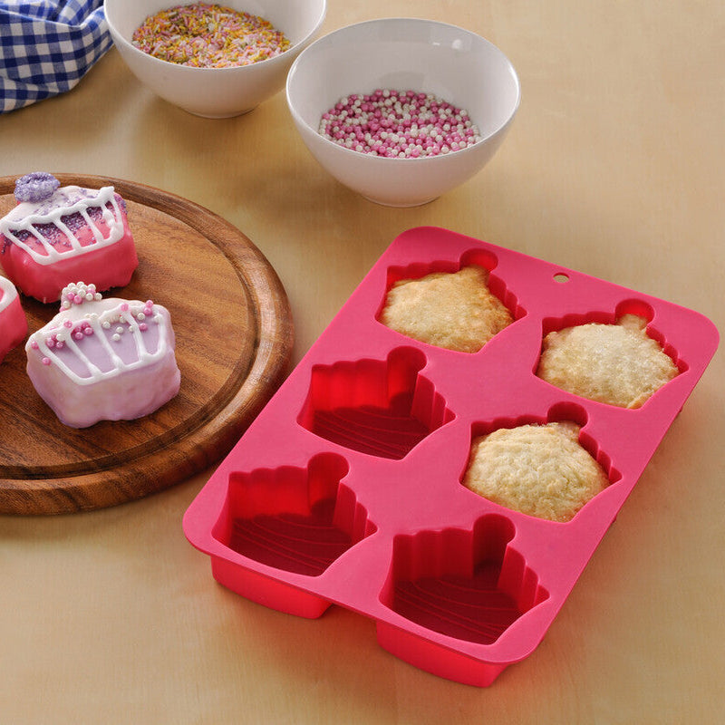 Silicone mold with cake-shaped cavities on a wooden board with decorative elements.