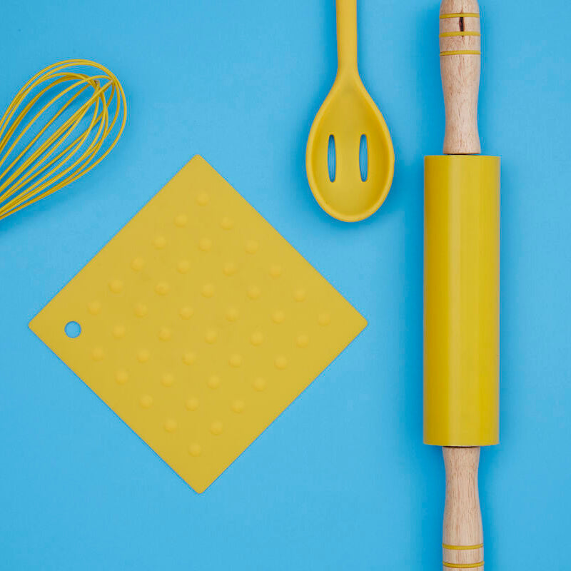Yellow kitchen utensils including a whisk, spatula, cutting board, and rolling pin on a blue background