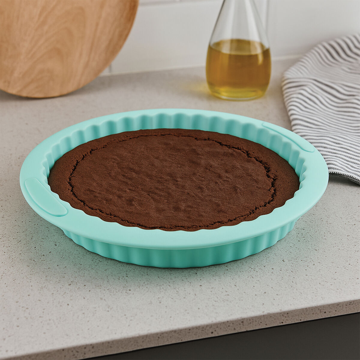 Chocolate cake in a turquoise silicone baking mold on a kitchen counter.