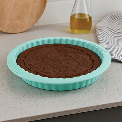Chocolate cake in a turquoise silicone baking mold on a kitchen counter.