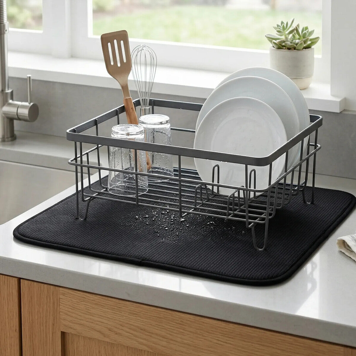 Dish drying rack with plates, glasses, and utensils on a kitchen counter.