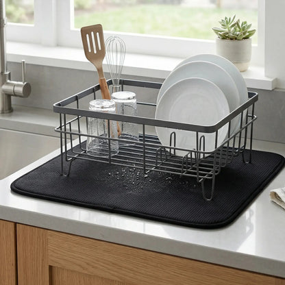 Dish drying rack with plates, glasses, and utensils on a kitchen counter.