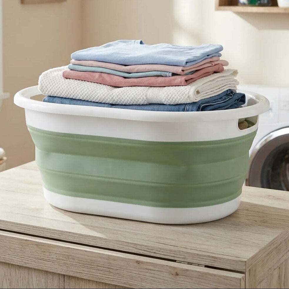 Green and white collapsible laundry basket with folded clothes on a wooden surface, with text &