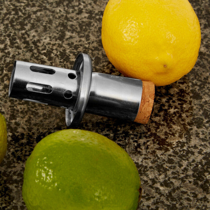 Metallic bottle opener with cork on a countertop with lemons and limes.