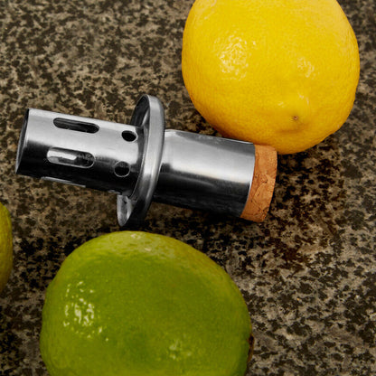 Metallic bottle opener with cork on a countertop with lemons and limes.