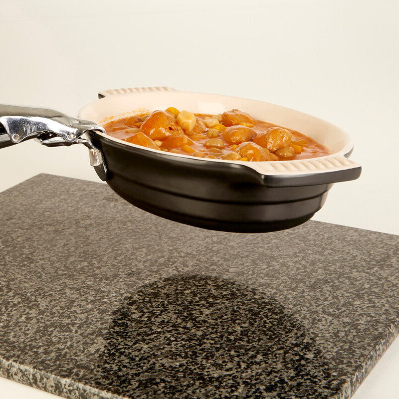 Person holding a portable frying pan with food over a stovetop