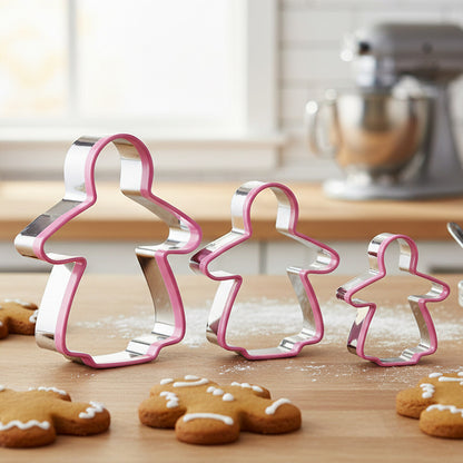 Set of gingerbread man cookie cutters on a wooden surface with decorated cookies.