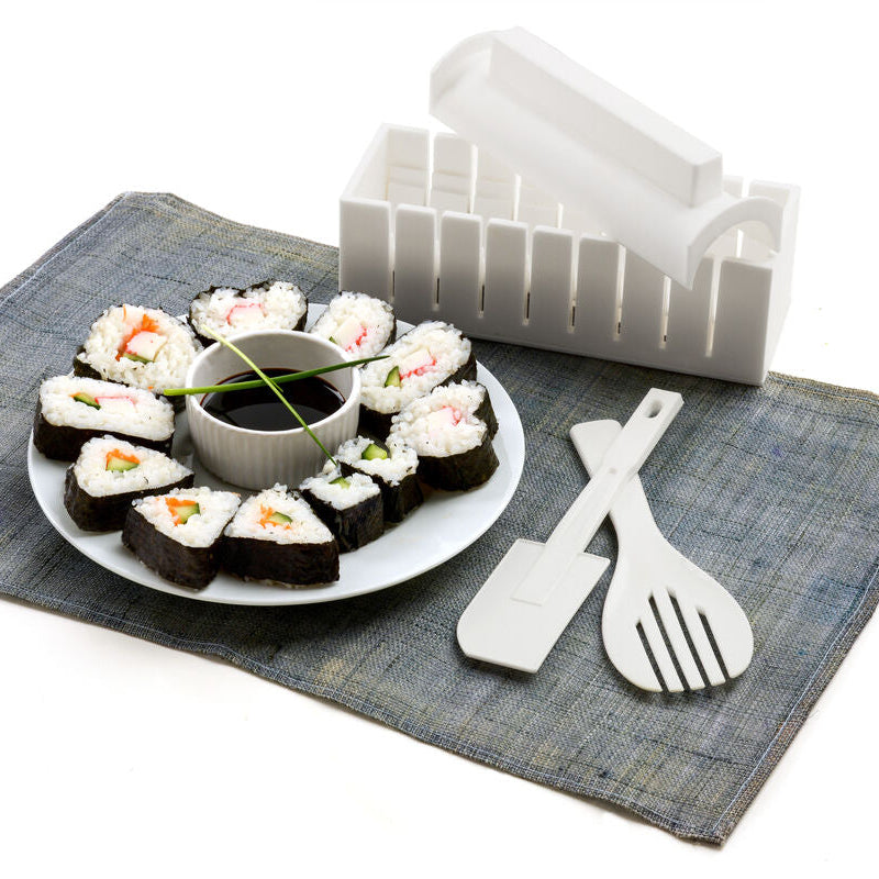 Assorted sushi on a plate with a small bowl of soy sauce and a set of white plastic utensils on a gray mat.