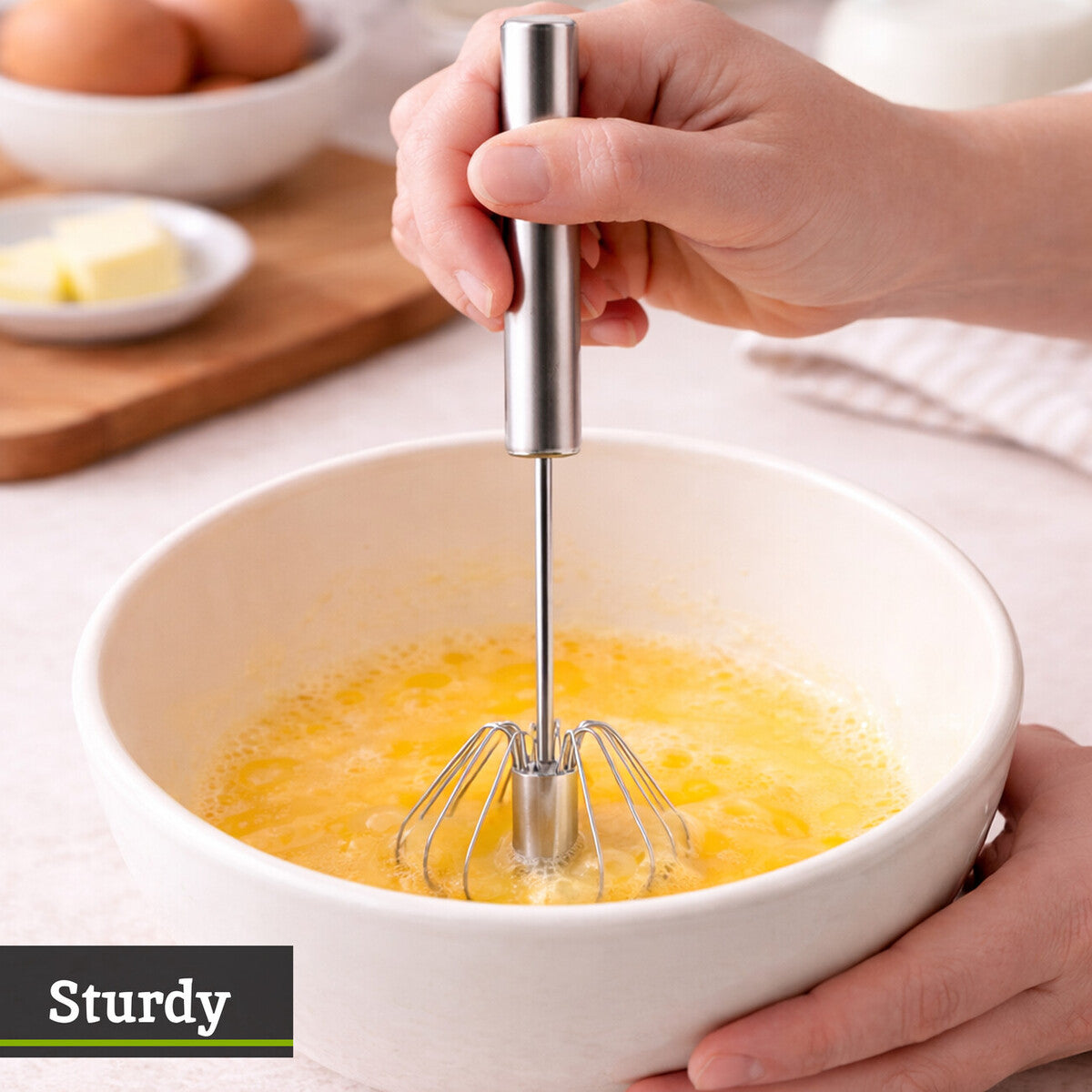 Hand using a hand mixer to whisk eggs in a bowl on a kitchen counter.