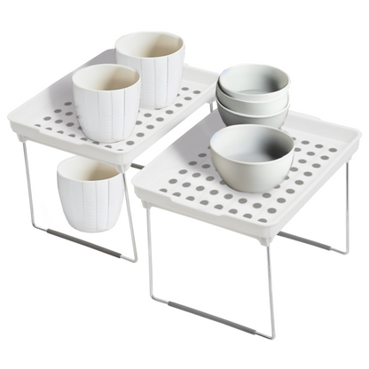 White ceramic cups and bowls on a metal stand with perforated design on a white background