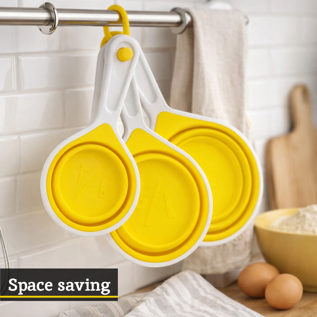 Yellow and white collapsible measuring cups hanging on a rack with kitchen items in the background.