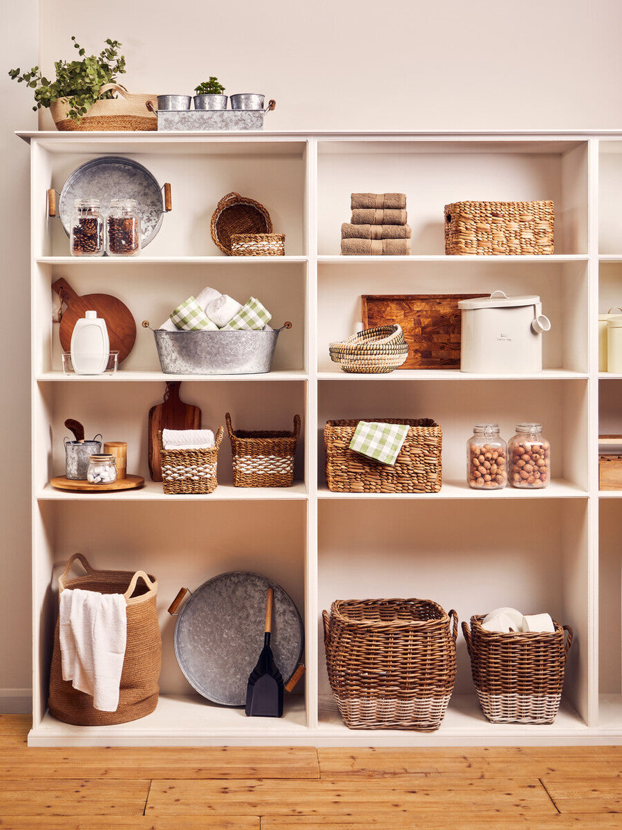 White shelving unit with various baskets and decorative items on a wooden floor.