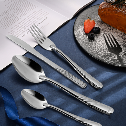 Silver cutlery set on a blue napkin with a dessert in the background