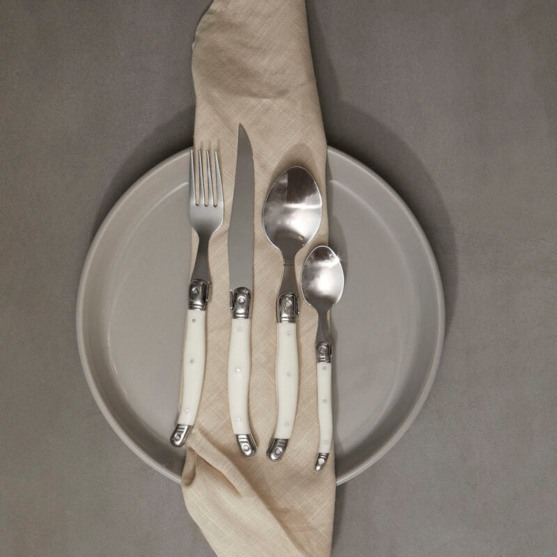 Set of silverware on a plate with a folded napkin against a gray background