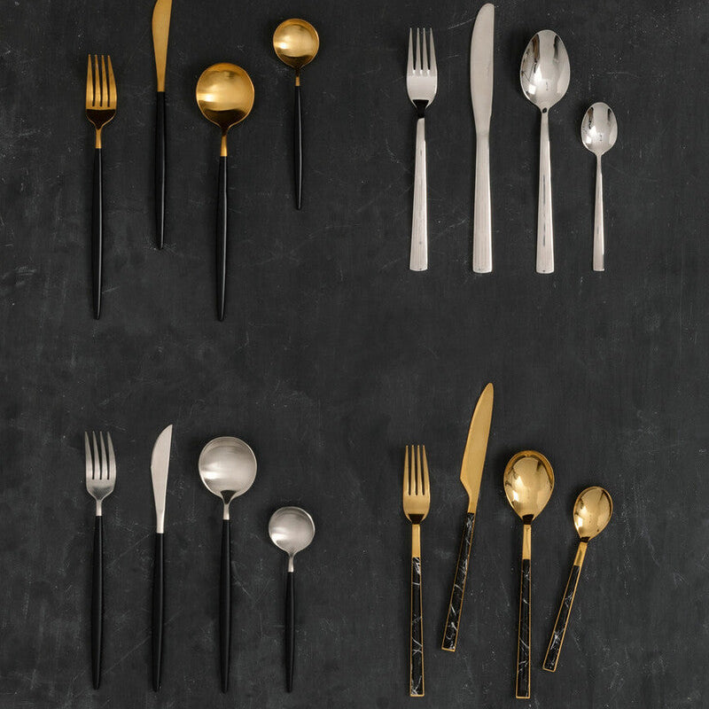 Set of gold and black flatware on a dark surface