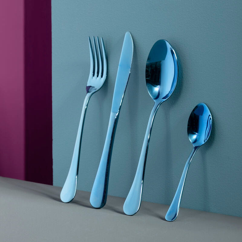 Set of silver cutlery including a fork, knife, and two spoons on a gray surface with a purple background.