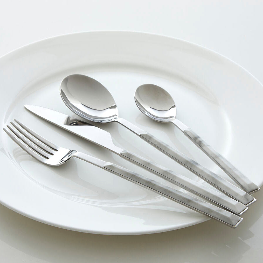 Silver cutlery set on a white plate with a white background