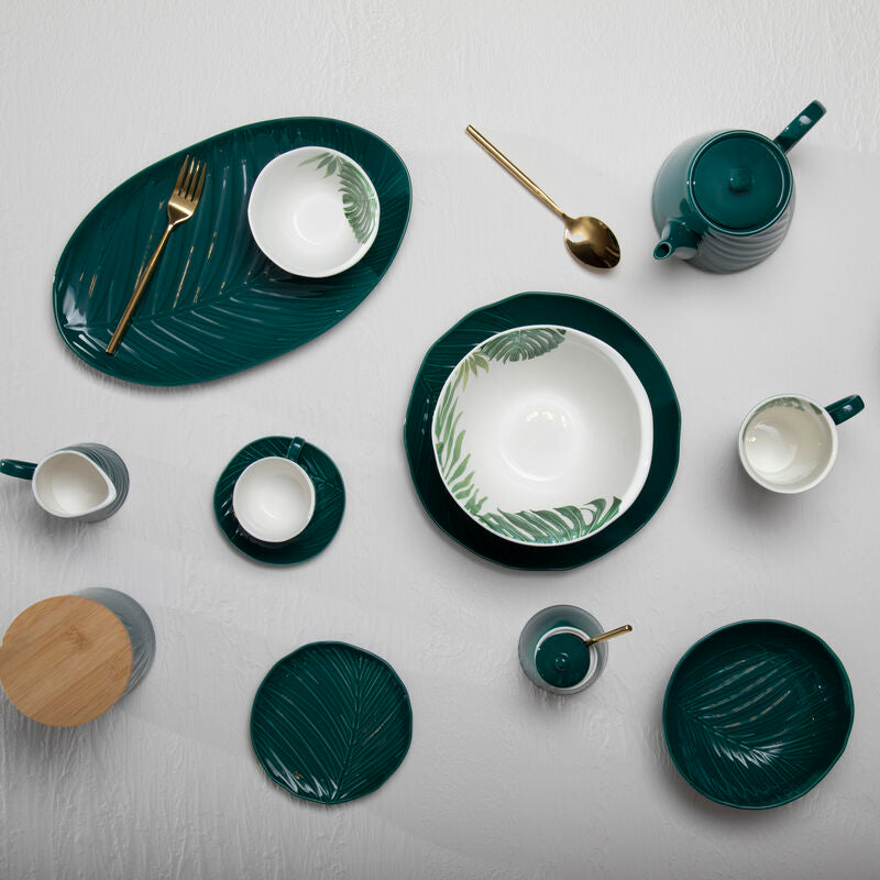 Collection of green and white ceramic tableware on a light gray background