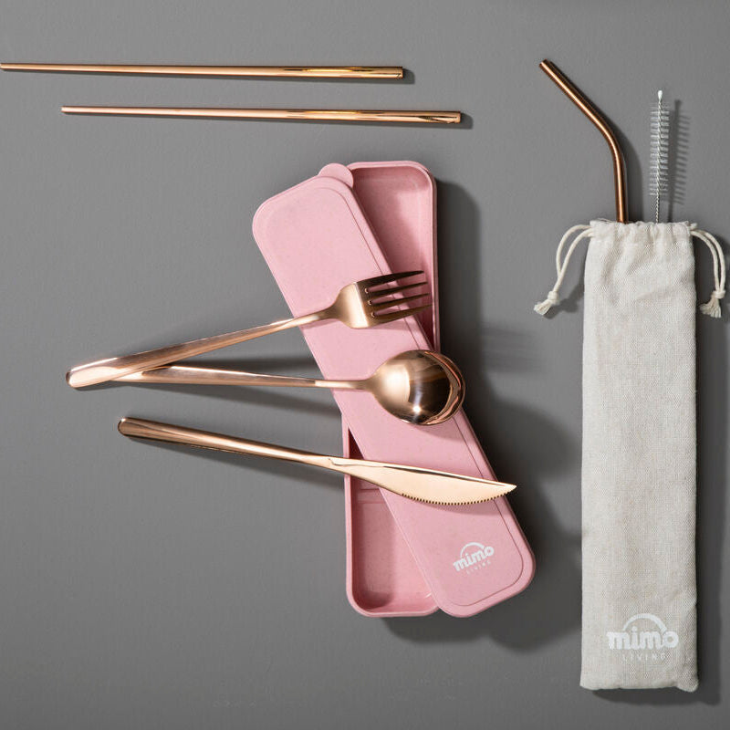 Set of gold cutlery with pink case and straw in a drawstring bag on a gray background