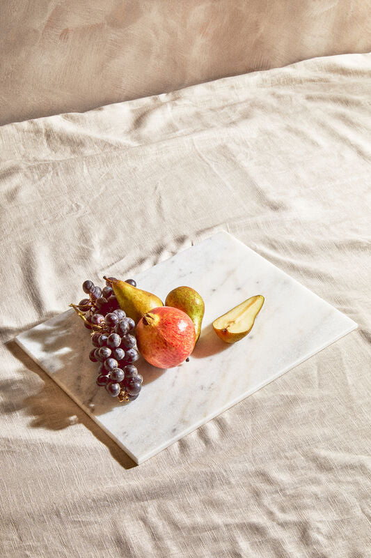 Fruit including grapes, pears, and an apple on a piece of paper with a beige background