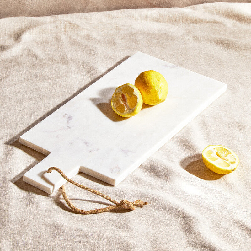 Marble cutting board with lemons on a beige surface