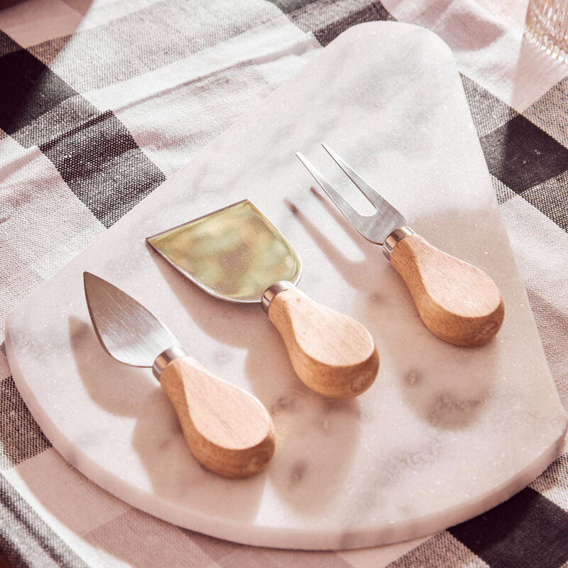 Set of cheese tools on a marble board with a checkered tablecloth