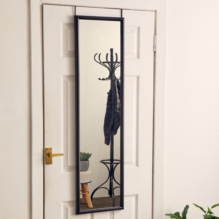 Entryway with a full-length mirror on a white door, coat rack, and small table with plant.