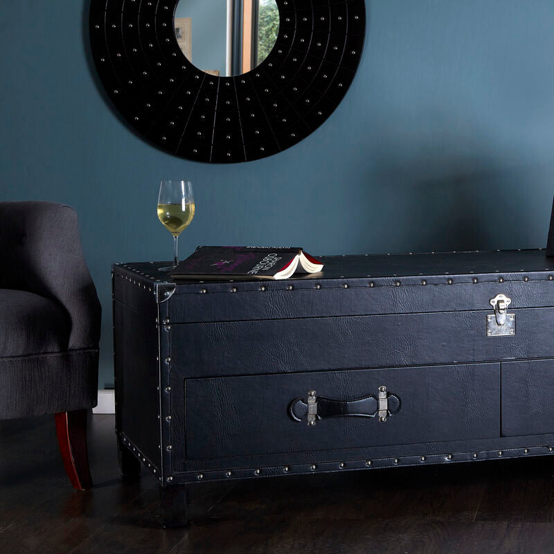 Black leather trunk with a glass of wine and book on a blue wall background