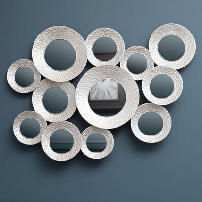 Decorative wall mirror with circular designs on a dark blue wall.