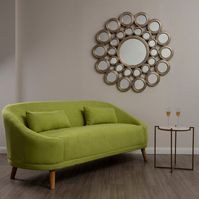 Green sofa in a room with a decorative mirror on the wall.